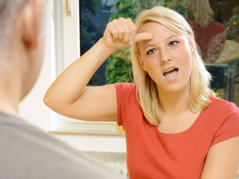 Gehörlose Frau kommuniziert in Gebärdensprache mit einem Mann