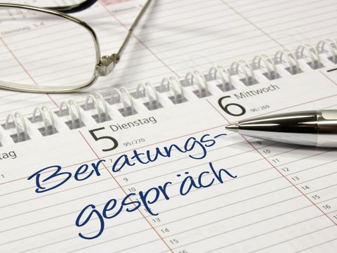In einem Terminkalender steht der Eintrag 'Beratungsgespräch'. Auf dem Kalender liegen ein Stift und eine Brille