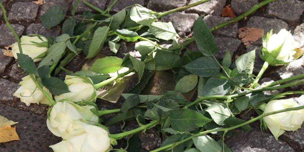 Weiße Rosen auf Stolperstein