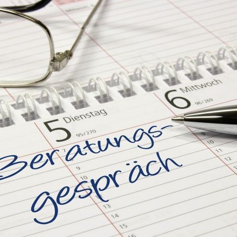 In einem Terminkalender steht der Eintrag 'Beratungsgespräch'. Auf dem Kalender liegen ein Stift und eine Brille