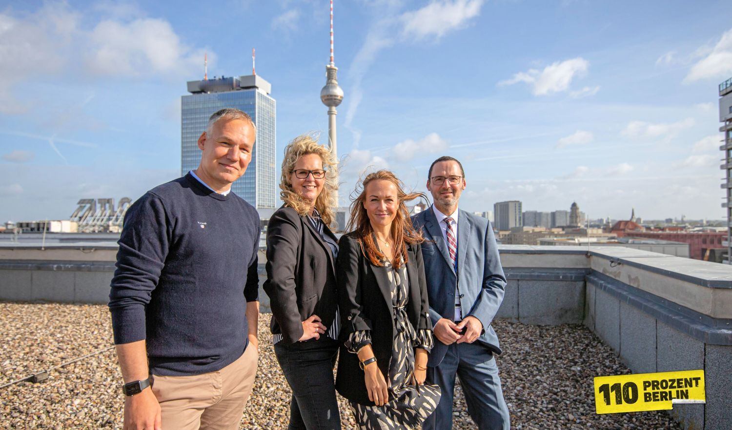 Vier Mitarbeiter auf dem Dach im Hintergrund der Alexanderplatz