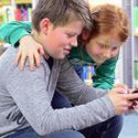 Bildvergrößerung: Bruder und Schwester nutzen in der Bibliothek ihr Smartphone mit HotsPlots