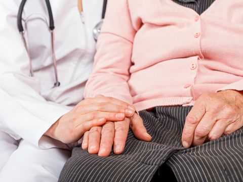 Medizinerin hält die Hand einer Seniorin