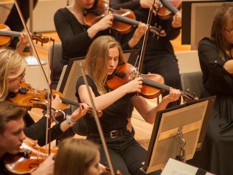 Frauen und ein Mann spielen Geige im Orchester