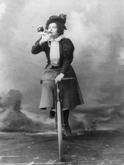 Schwarz-weiß Bild einer Frau, die auf einem Rad sitzt und in ein Sprachrohr spricht