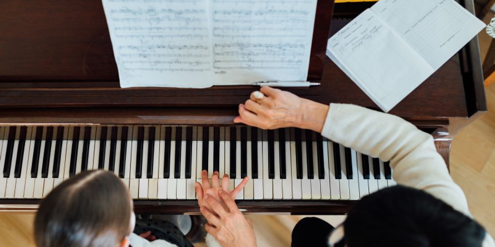 Musiklehrerin hilft Schülerin beim Klavier spielen