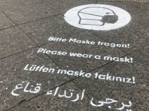 Das Bild zeigt das Graffiti "Bitte Maske tragen" in vier Sprachen.