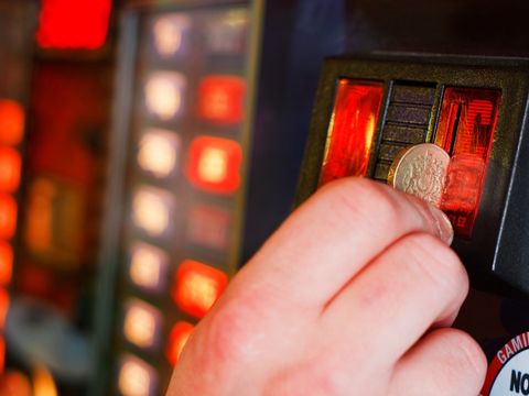 Eine Person wirft eine Münze in einen Spielautomat