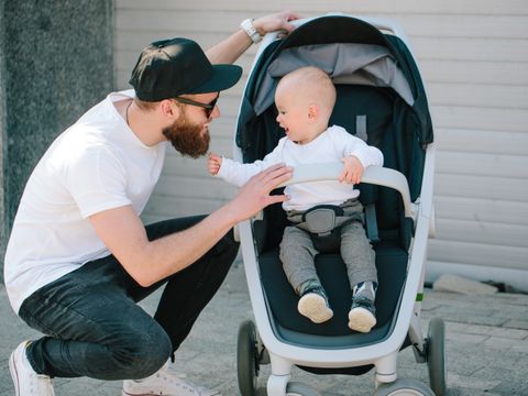 Vater mit einem Kinderwagen und ein Baby in den Straßen der Stadt zu Fuß