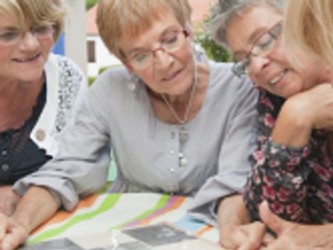 Vier ältere Damen schauen sich ein Fotoalbum an