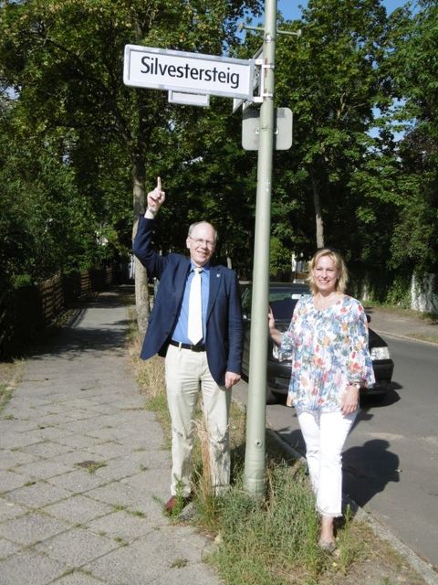 Bildvergrößerung: Bezirksstadträtin Katrin Schultze-Berndt (CDU) und der Bürgermeister der Gemeinde Glienicke/ Nordbahn Dr. Hans G. Oberlack (FDP) vor dem neuen Straßenschild „Silvestersteig“