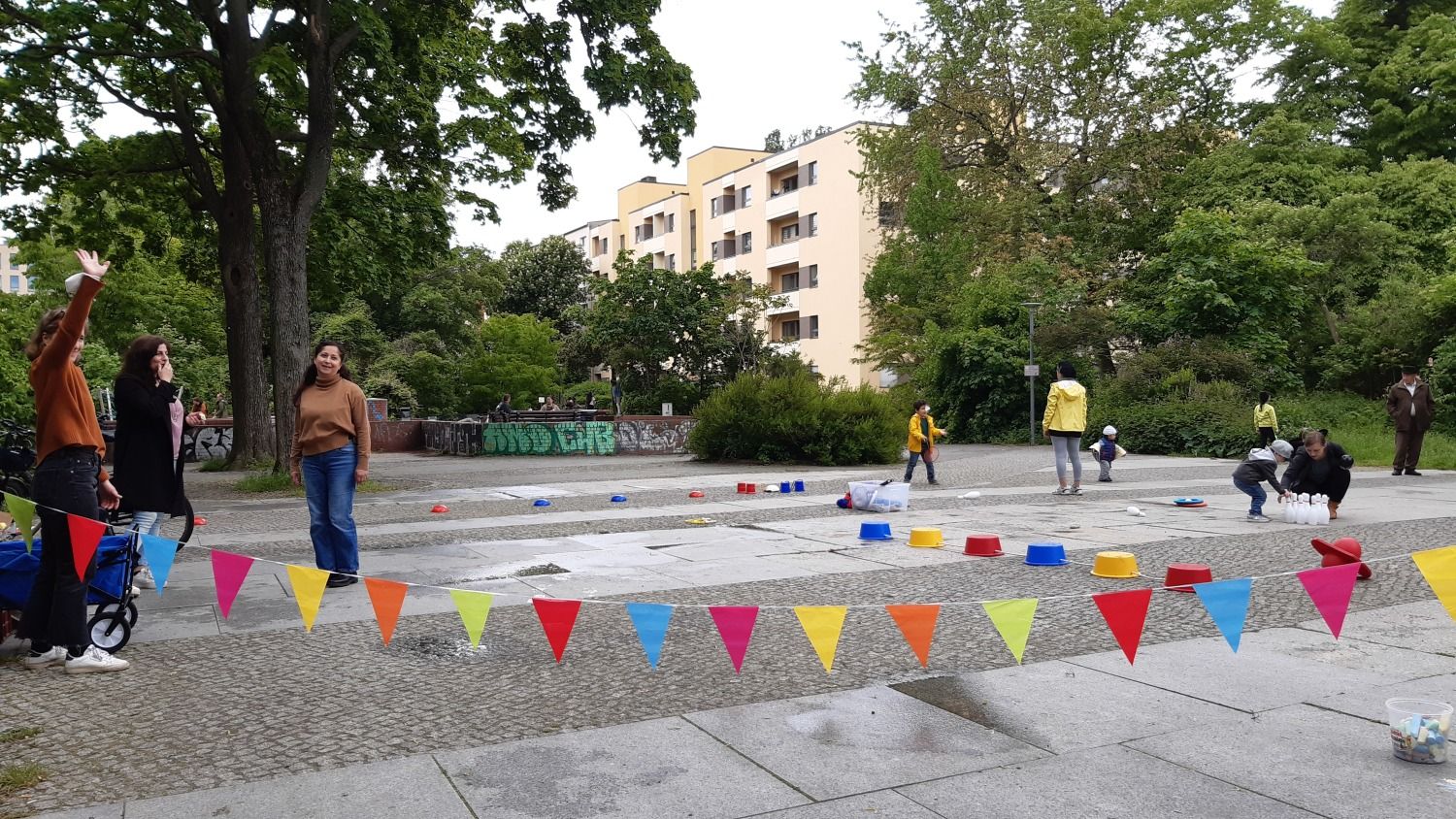 spielende Kinder auf einem Bewegungsparkour am Vinetaplatz und sich unterhaltende Erwachsene