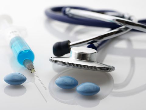 Ein Stethoskop, eine Spritze und Tabletten liegen auf einem Tisch