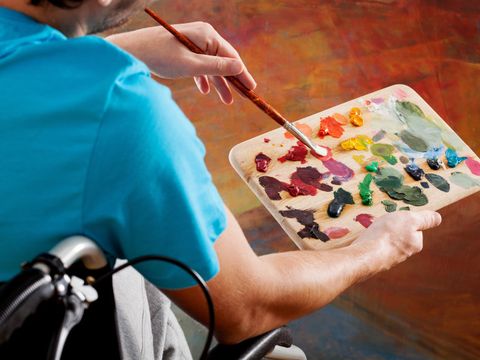 Bildvergrößerung: Ein Mann im Rollstuhl mischt Farben auf einer Palette