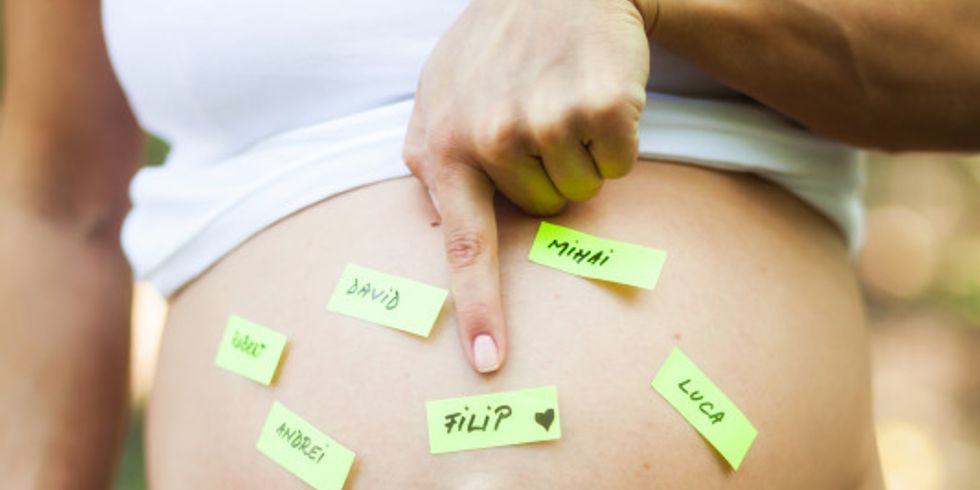 Schwangere Frau mit Postit-Zetteln auf dem Bauch