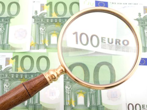 Lupe über grünen 100-Euroscheinen