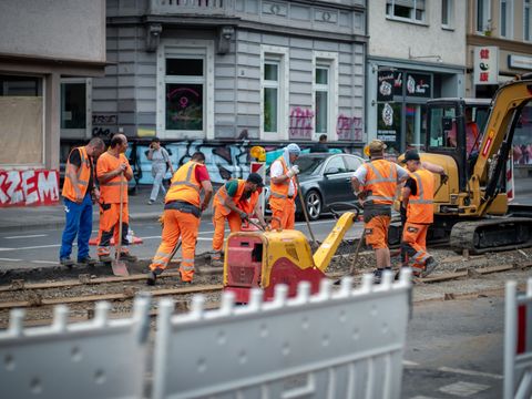 Beschäftigte im Straßenbau bei Arbeiten an einem Straßenbahngleis 