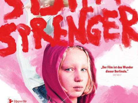 Filmtitel „Systemsprenger“ und Portrait der Hauptdarstellerin - ein Mädchen in rosafarbener Jacke mit Kaputze