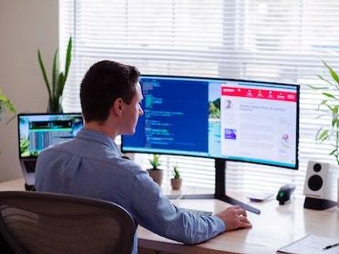 Ein Mann arbeitet an einem Schreibtisch vor einem Computerbildschirm
