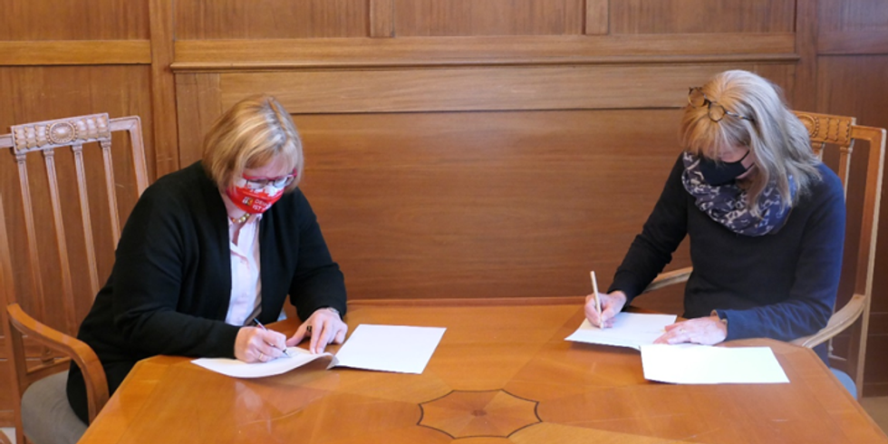zwei Frauen unterschreiben n einem Tisch Dokumente