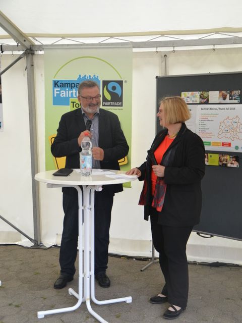 Moderator Klaus Brückner interviewt Bezirksbürgermeisterin Angelika Schöttler. Beide stehen an einem Stehtisch in einem Pavillon