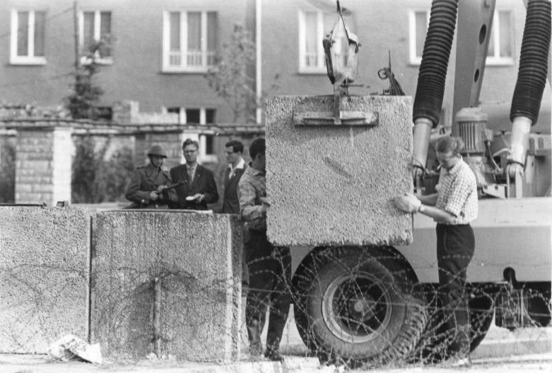 Berlin - Mauerbau, Aufstellen von Betonblöcken mit einem Kran hinter Stacheldraht
