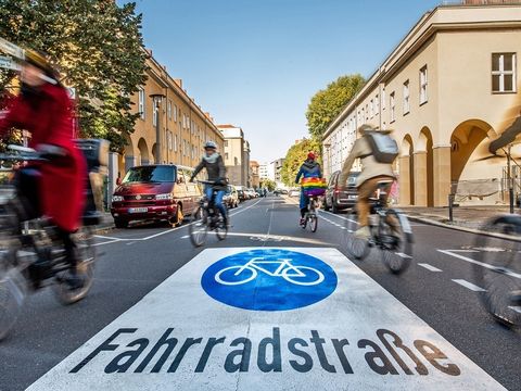 Blick in eine Straße mit Radfahrenden und einem Schild mit der Aufschrift "Fahrradstraße"