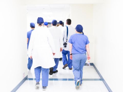 Ärzte und Pflegerinnen laufen einen Gang entlang