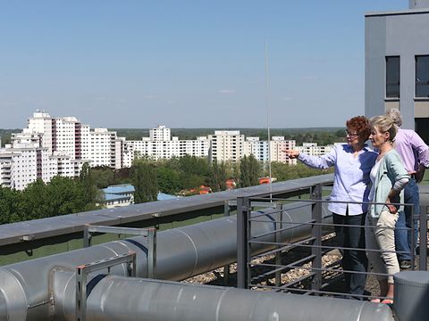 Zwei Frauen blicken von der Dachterrasse auf die Großsiedlung