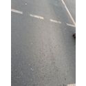 Bildvergrößerung: Foto eines Ausschnitts einer geteerten Straße mit weißer Markierung