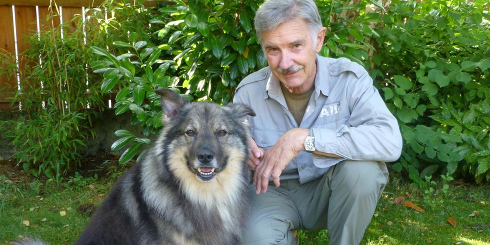 Josef Reichholf hockt mit seinem Hund auf einer Wiese