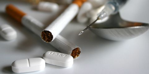 Zigaretten, Tabletten, Löffel und Spritze liegen auf einem Tisch