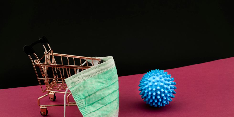 Einkaufswagen mit Mundschutz und ein Ball davor, der das Coronavirus symbolisiert 