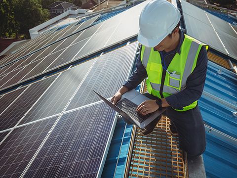 Arbeiter kontrolliert Solarpanel auf einem Dach - KEK