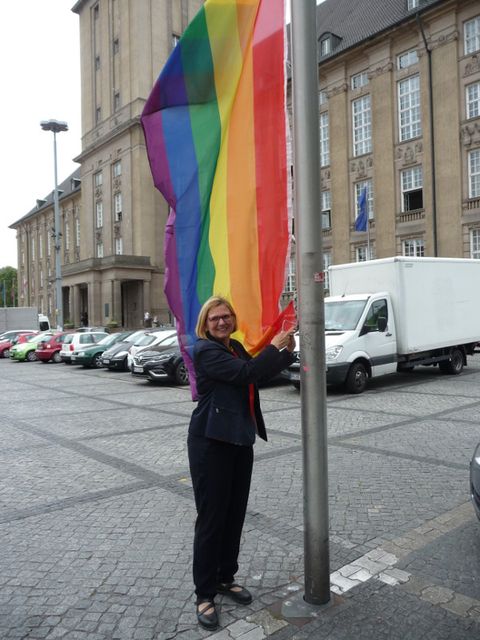 Bildvergrößerung: Eine Frau beim Hissen der Regenbogenflagge