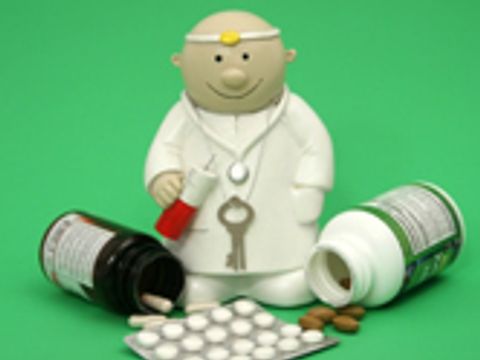 Eine Arztfigur mit Tablettenbehälter und Tabletten vor sich auf grünem Hintergrund