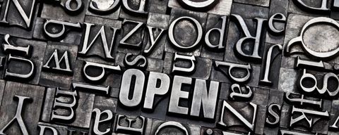 Wort "Open" zusammengesetzt aus Bleilettern, mit vielen weiteren Buchstaben im Hintergrund