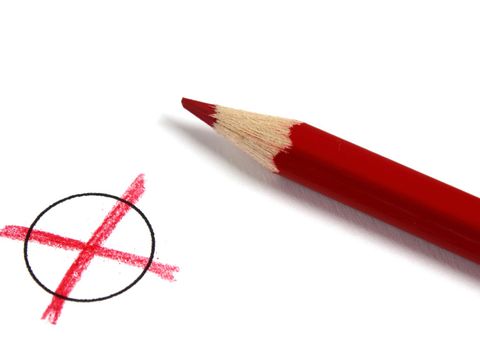 Ein roter Buntstift macht ein Kreuz in einem Kreis