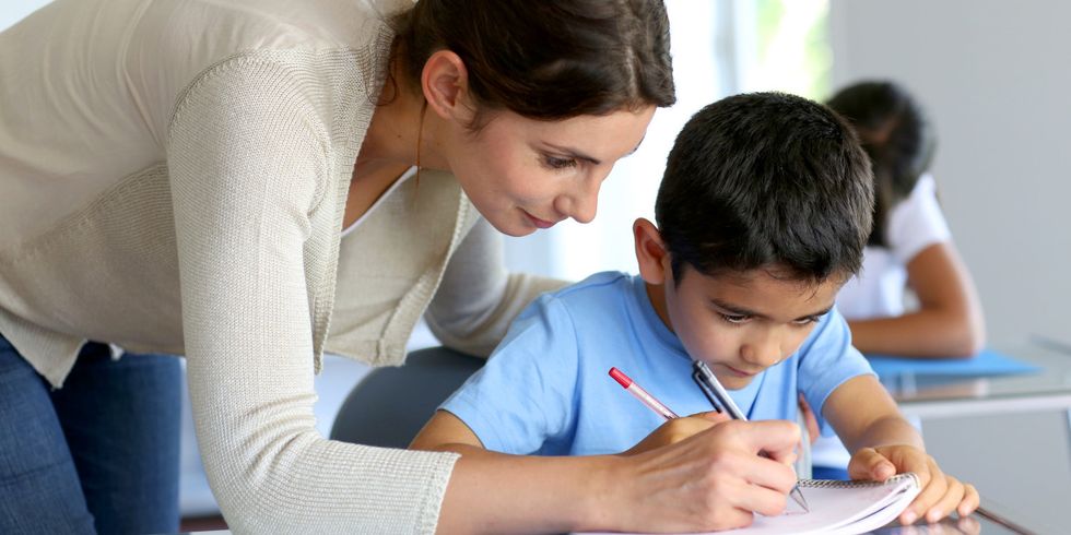 Lehrerin hilft kleinem Jungen bei den Hausaufgaben