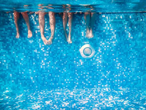 Beine von Kindern und Erwachsenen im Schwimmbad unter Wasser