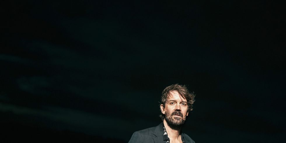 Das Farbfoto zeigt den Musiker Niels Frevert frontal vor schwarzem Hintergrund.
