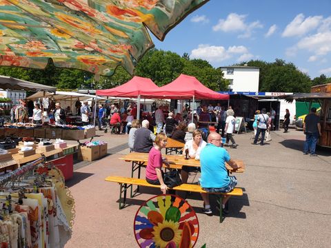 Wochenmarkt Britz Süd Marktatmosphäre mit Personen auf der Bierbank und mehreren Stoffmarktständen im Hintergrund