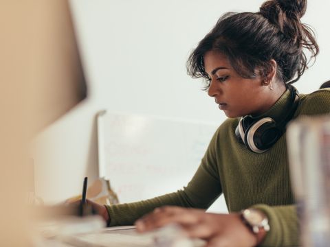 Eine Frau mit Kopfhörer arbeitet an einem Schreibtisch