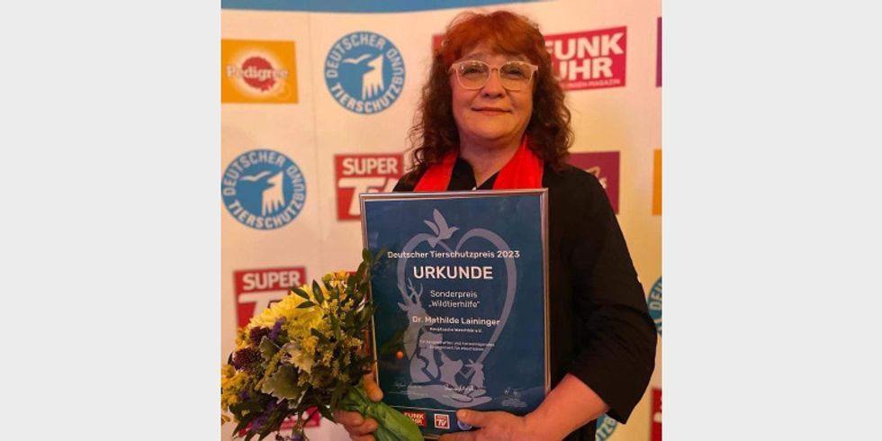 Frau Dr. Mathilde Laininger hält die Urkunde des Deutschen Tierschutzpreises 2023 und einen Blumenstrauß in den Händen