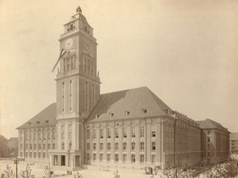 ein großes Gebäude mit Turm auf einer vergilbten Postkarte