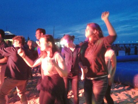 Mehrere junge Leute tanzen am Strand