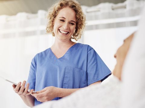 Eine lächelnde Krankenpflegerin spricht mit einem liegenen Patienten