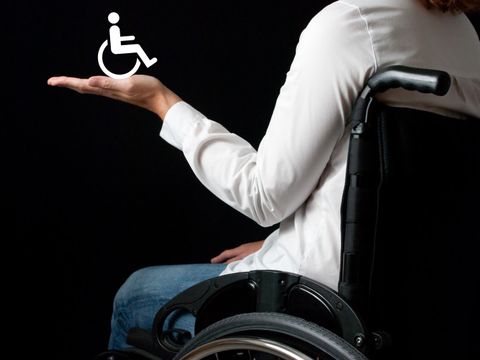 Rollstuhlfahrer mit Rollstuhlpiktogramm auf der Hand