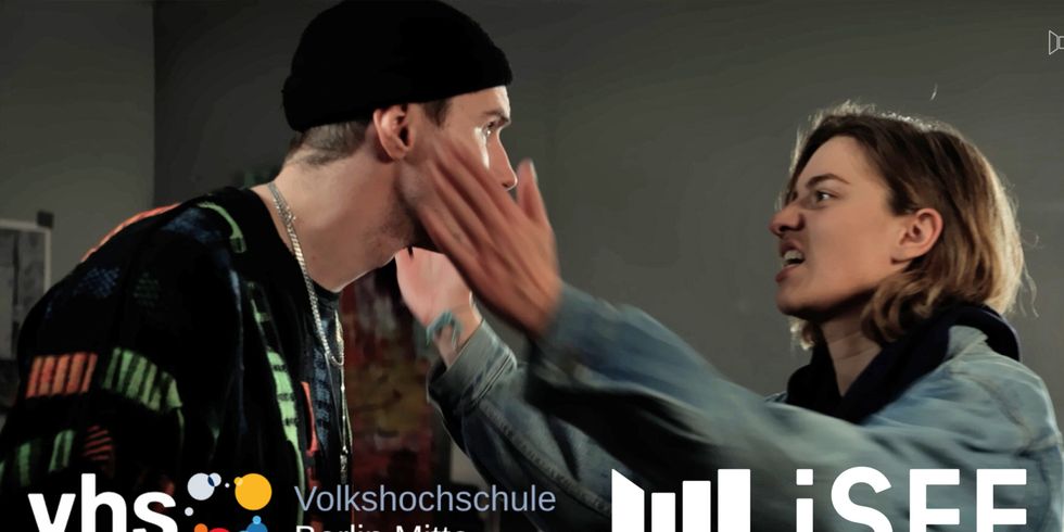 Trailer-Titelbild: Logos der vhs Berlin Mitte und des iSFF. Szenen-Screenshot von zwei Personen. Eine Person hält die Hände vor das Gesicht der anderen und deutet einen Schlag an.