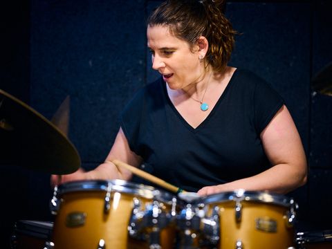 Portrait der Kursleiterin Claudia Hoppe die am Schlagzeug trommelt